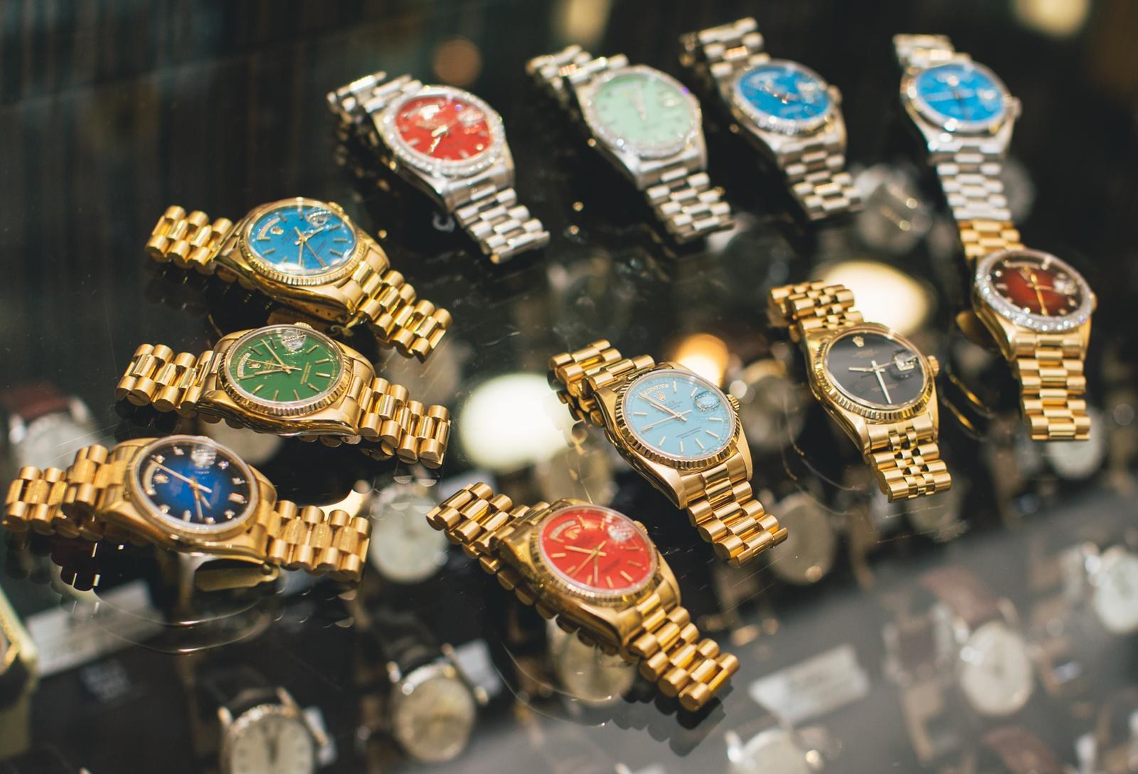 Photograph of vintage 1970s Rolex Day-Date watches in yellow and white gold set with brightly colored lacquered Stella dials in blue, green, coral red and black
