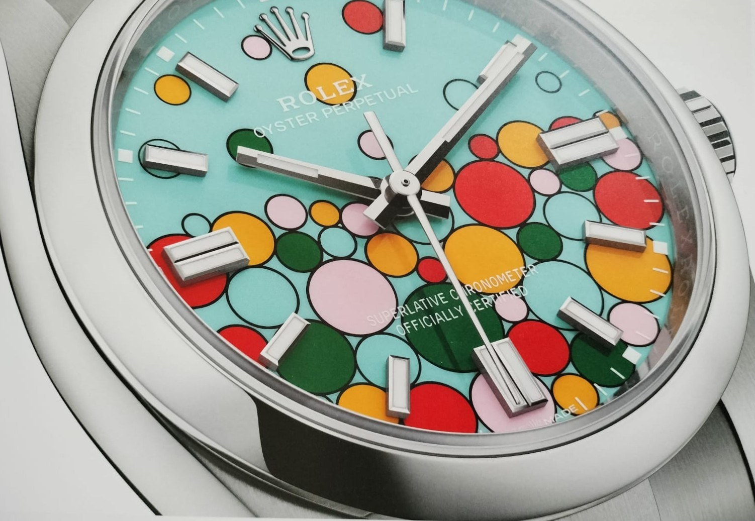 Close-up photograph of a stainless steel Rolex Oyster Perpetual with the turquoise Celebration dial scattered with multi-colored lacquer bubbles